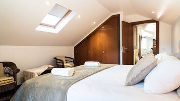 Un dormitorio con tragaluz, una cama con almohadas, una silla y un armario de madera.
