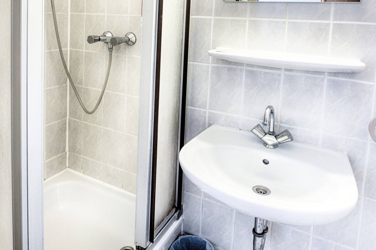 Une salle de bain avec une douche, un lavabo et un miroir.