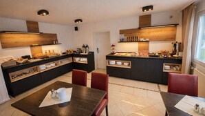 Een moderne keuken met een centraal eiland, inbouwapparatuur en een eethoek met een tafel en stoelen.