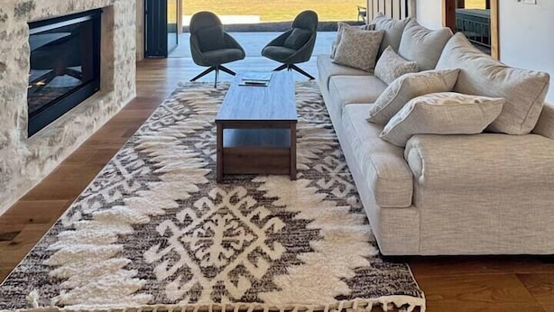 A spacious living room with a fireplace, a large sofa, and a view of the countryside. - Sunday House at The Sanctuary (Gillespie County)