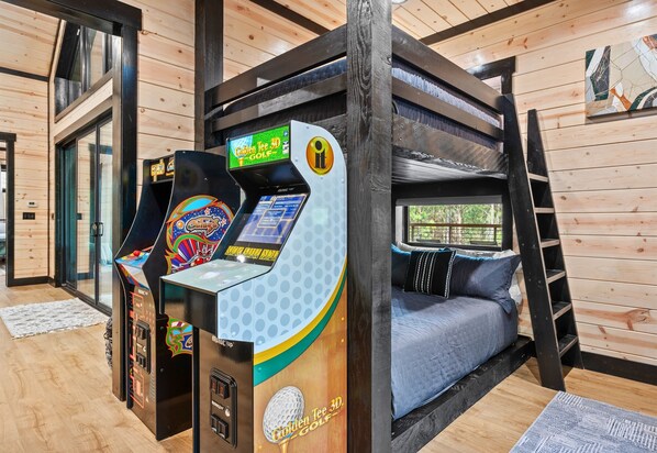 A bunk bed room with a 3D golf arcade game and a window with a view.