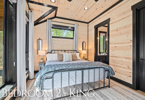 A bedroom with a bed, bedside tables, a window, and a door.