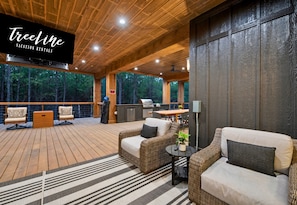 A covered outdoor area with wicker furniture, a grill, and a dining table.