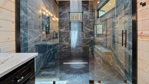 Un baño moderno con ducha tipo cascada central, baldosas hexagonales en el suelo y paneles de madera.