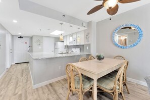 A modern kitchen with white cabinets, a granite countertop, and a ceiling fan. - Steps to the Sand, Endless Ocean Views – Book Now! 2 bedroom, 2 full bath! (Myrtle Beach)