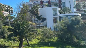 A modern hotel with a white facade, large windows, and a flat roof.