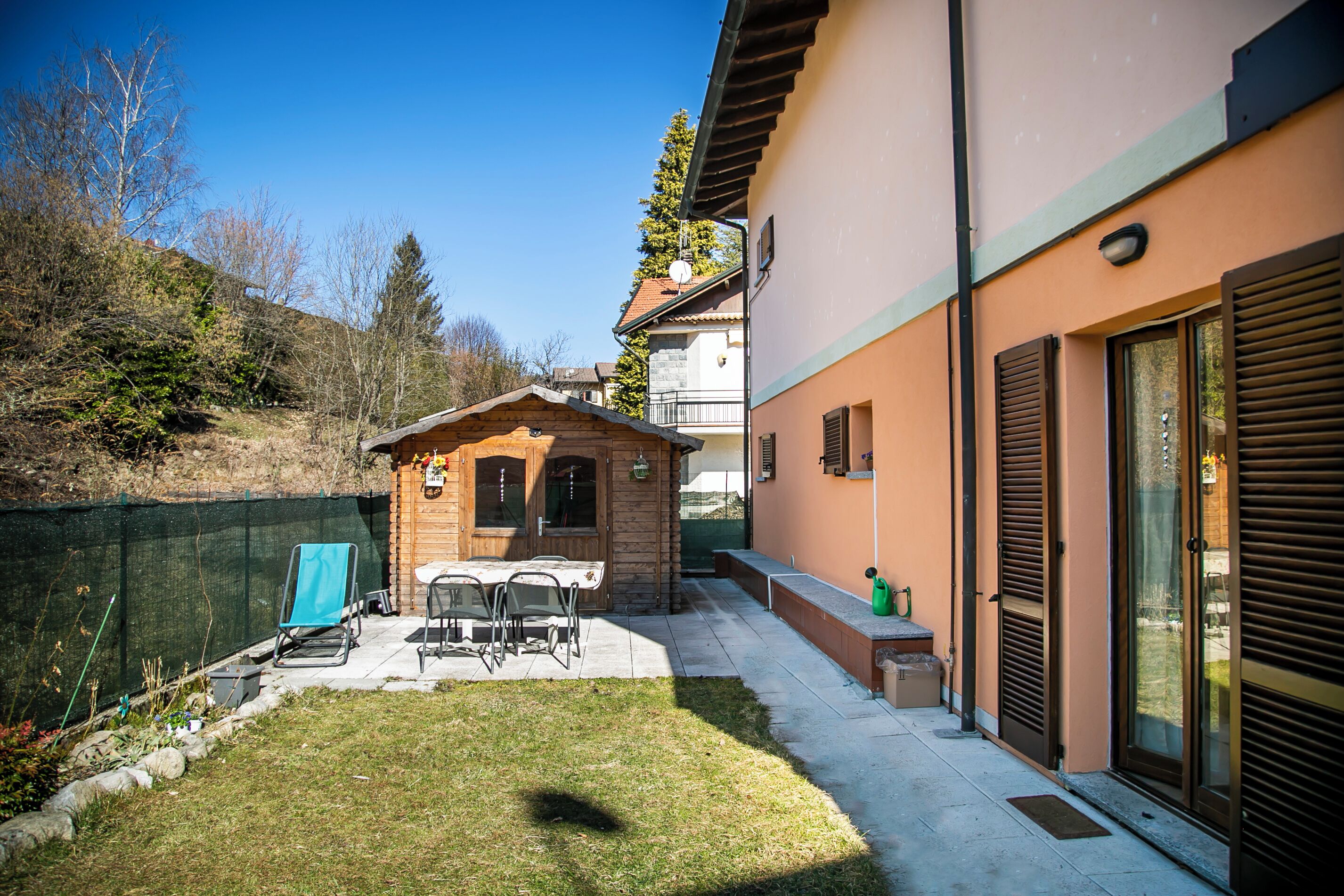 A residential property with a patio, outdoor seating, and a small wooden structure.