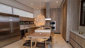 Una cocina moderna con una isla central, electrodomésticos de acero inoxidable y una lámpara colgante.