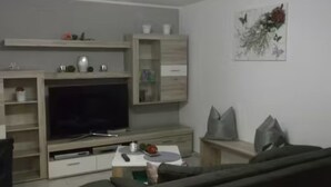 Un salon doté d’un téléviseur à écran plat, d’étagères en bois et d’un tableau accroché au mur.