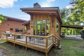 Una cabaña de madera con un porche, mobiliario exterior y una zona de barbacoa.
