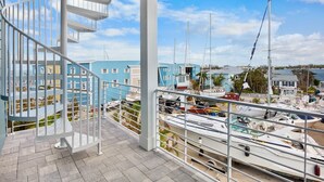 A balcony with a spiral staircase, overlooking a marina with several boats and colorful buildings in the background. - Take A Dip- Luxury 6 bedrooms, close to beach, pool and spa!! (Bradenton Beach)