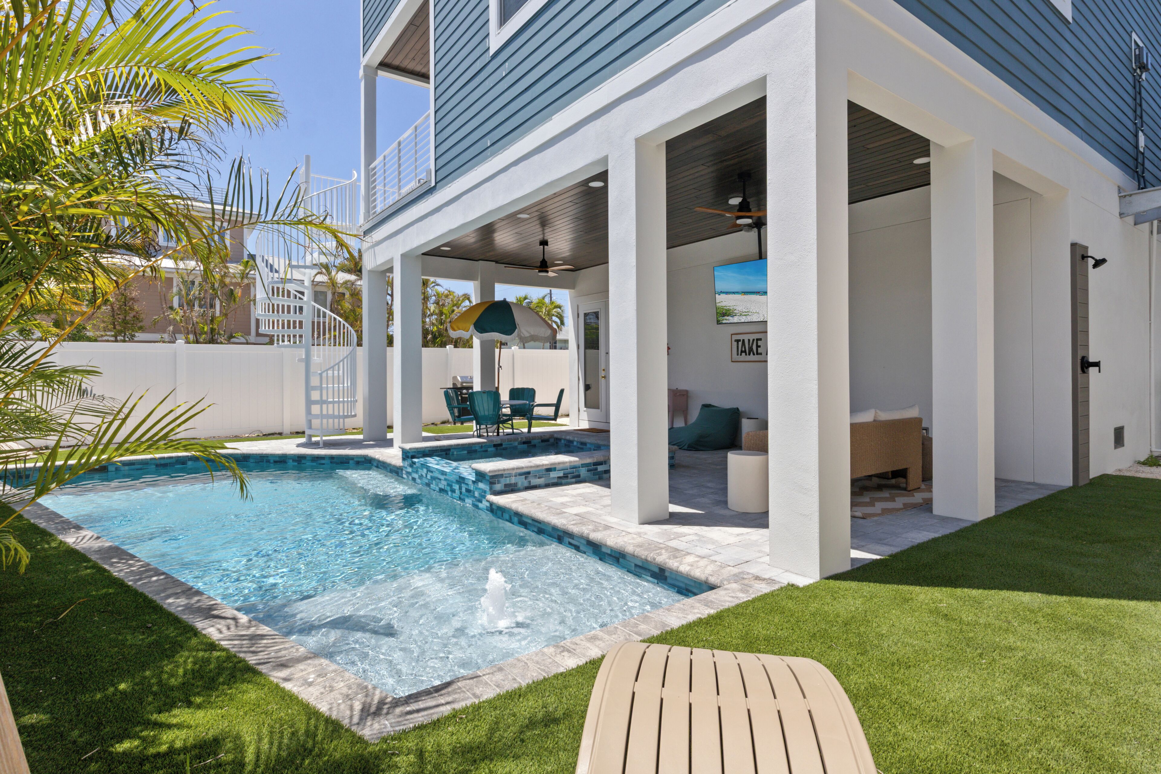 A modern house with a swimming pool, outdoor seating, and a covered patio area.