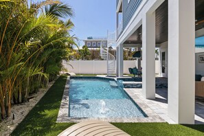 Una piscina con cubierta blanca, rodeada de palmeras y una cerca blanca.