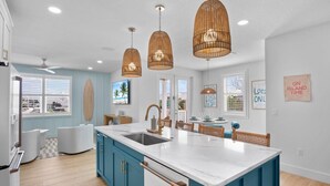 A modern kitchen with a large island, white and blue cabinetry, and pendant lights. - Take A Dip- Luxury 6 bedrooms, close to beach, pool and spa!! (Bradenton Beach)