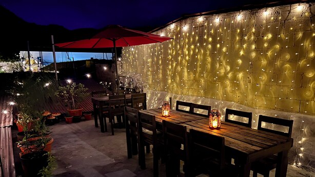 An outdoor patio with wooden tables and chairs, string lights, and potted plants. - Enchanted Forest (Antigua Guatemala)