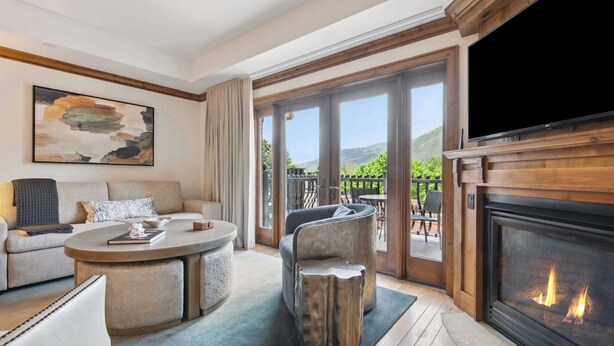 A modern living room with a fireplace, a large TV, and a view of the outdoors.
