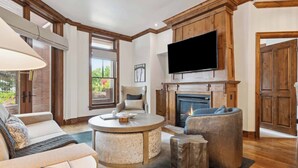 A cozy living room with a fireplace, comfortable seating, and a flat-screen TV mounted above it.