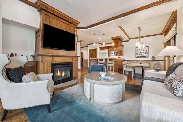 A spacious living room with a fireplace, a television, and a round coffee table.