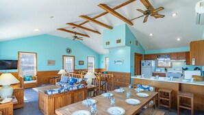 A spacious living area with a high ceiling, wooden beams, and a dining table set for four. - Semi-oceanfront home on the 4x4 beaches with gorgeous views! (Carova)