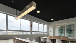 A modern office space with a long wooden reception desk, white chairs, and large windows offering a city view. - Beautiful Apartment in Lima (Lima)