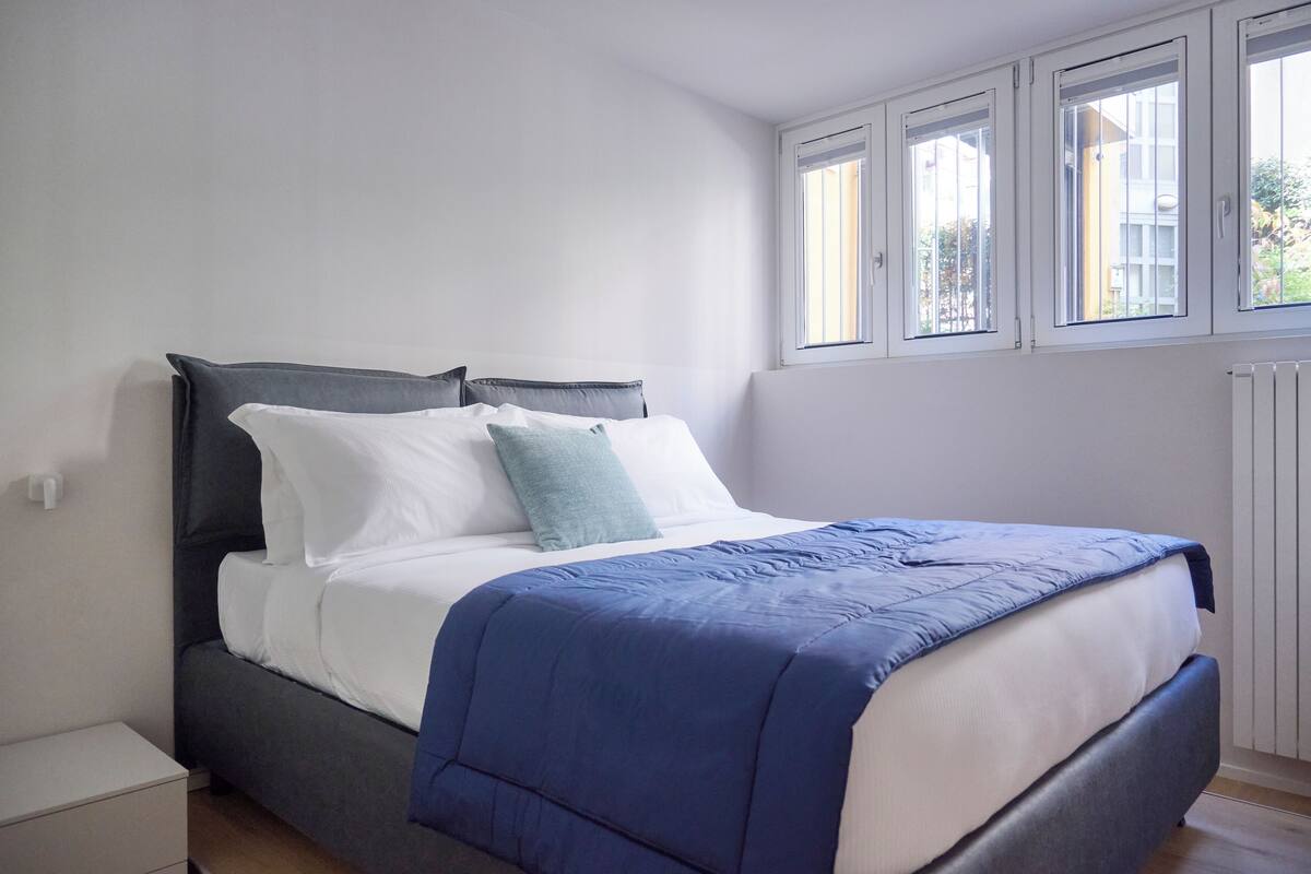 Une chambre à coucher avec un lit, une table de chevet et une fenêtre avec des stores.