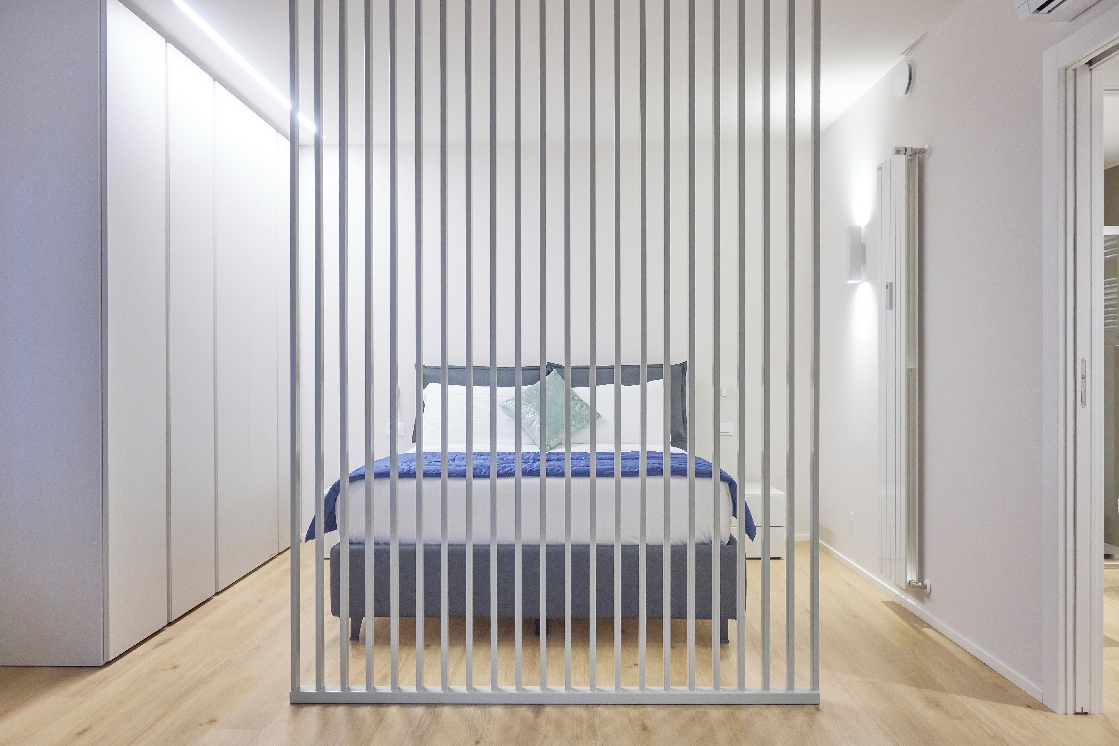A bedroom with a bed, a wardrobe, and a radiator.