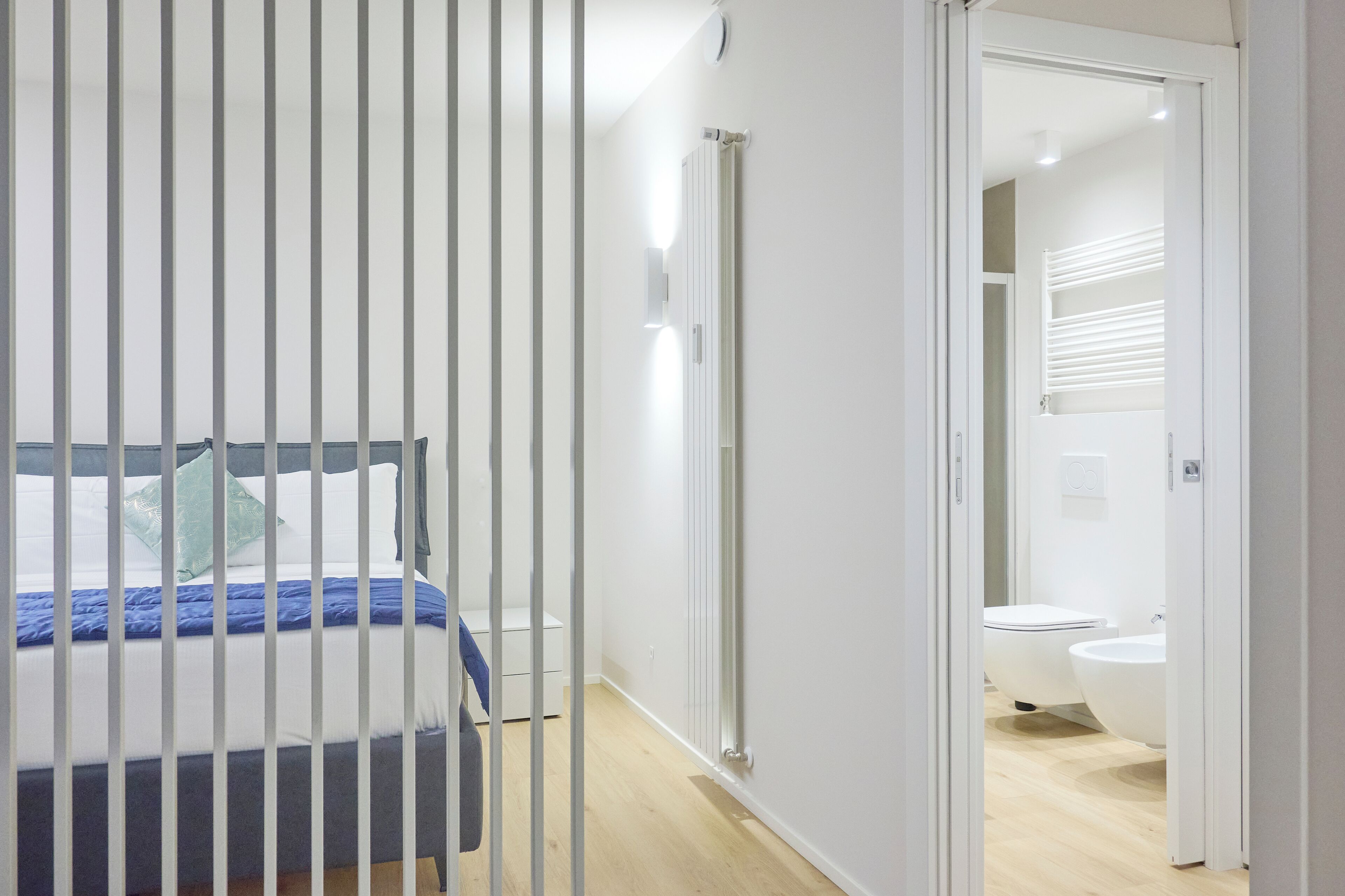 Un dormitorio moderno con cama, radiador y baño que incluye inodoro y bidé.