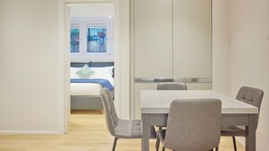 Une chambre moderne avec une table et des chaises, un lit donnant sur une vue agréable et une grande armoire.