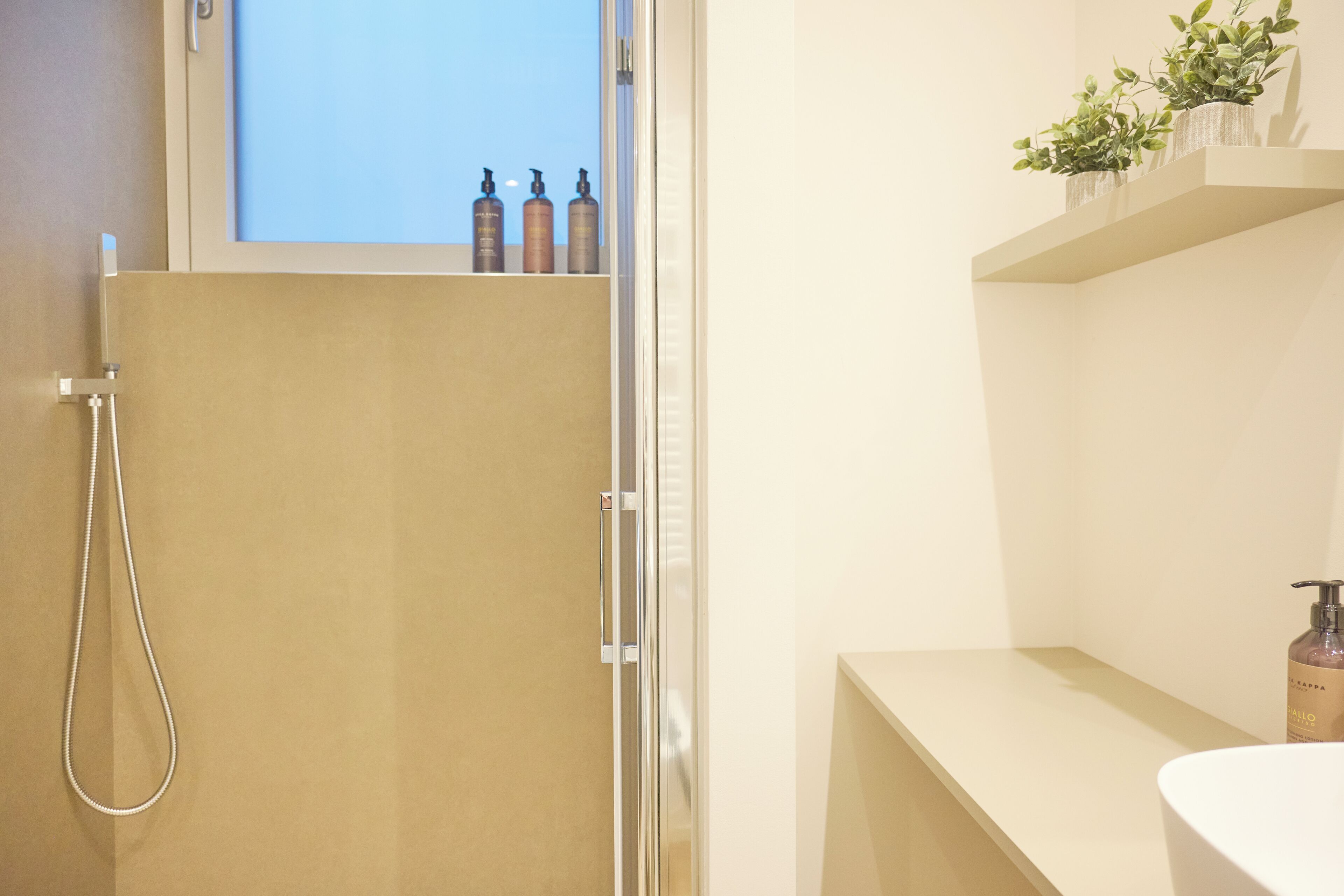 Une salle de bain avec une douche, un lavabo et une fenêtre située au-dessus du lavabo.