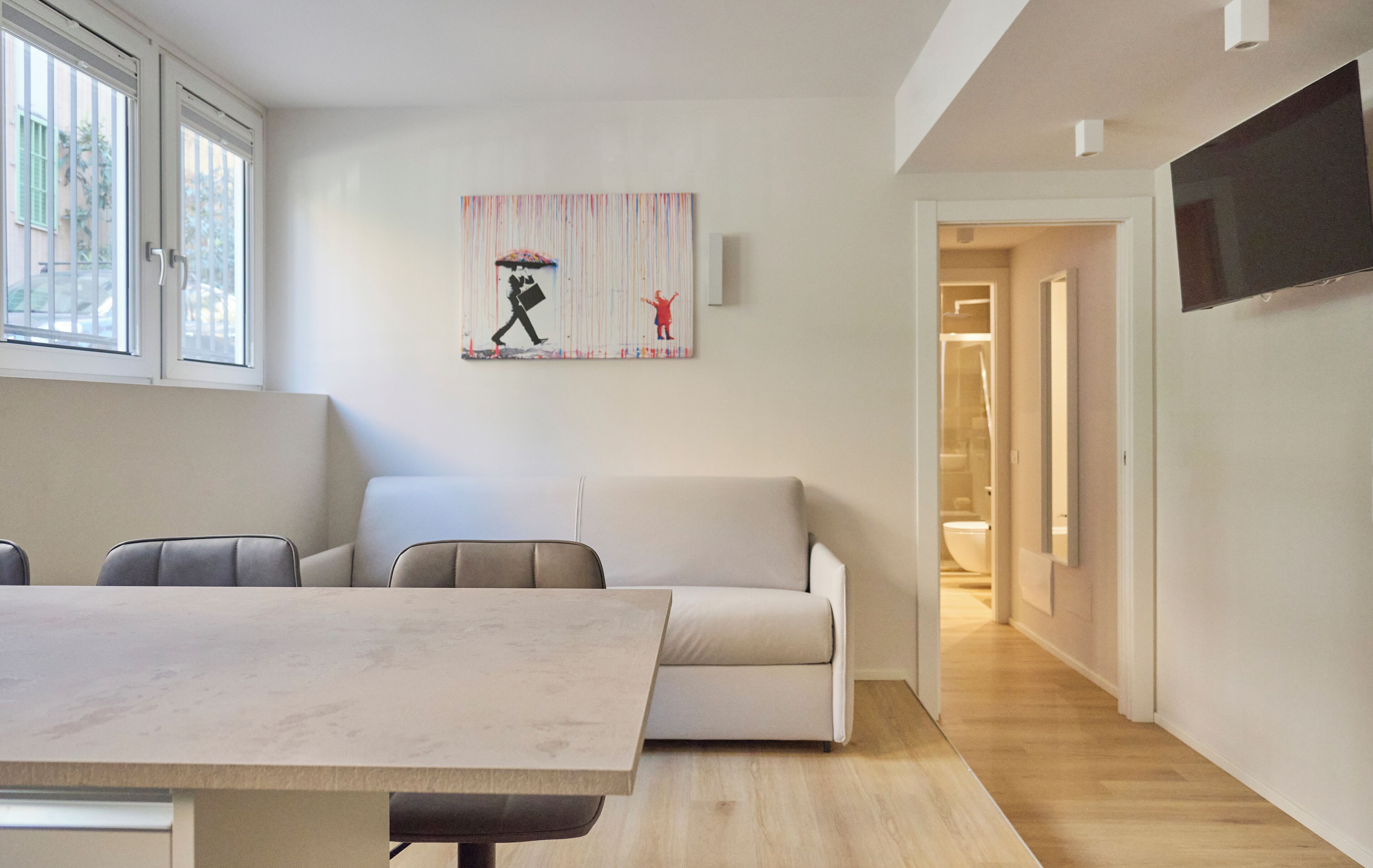 Een moderne woonkamer met een eettafel, een bank en een schilderij aan de muur.