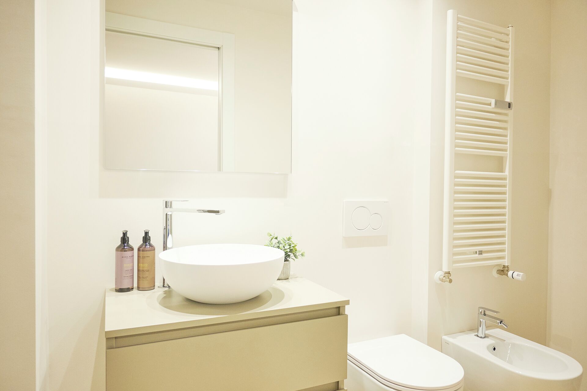Ein modernes Badezimmer mit Waschbecken, Waschtisch und Toilette. Über dem Waschbecken hängt ein Spiegel und an der Wand ist ein Handtuchhalter.