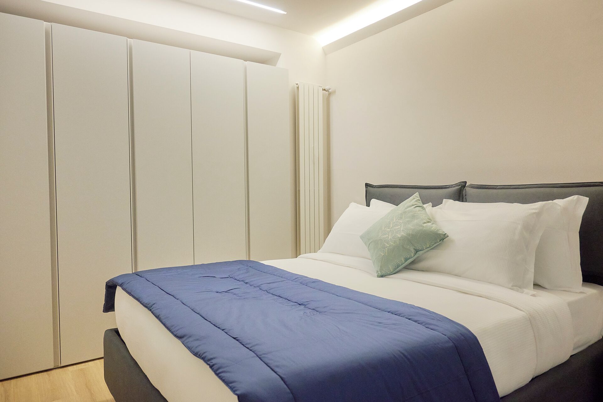 A bedroom with a bed, a wardrobe, and a radiator.