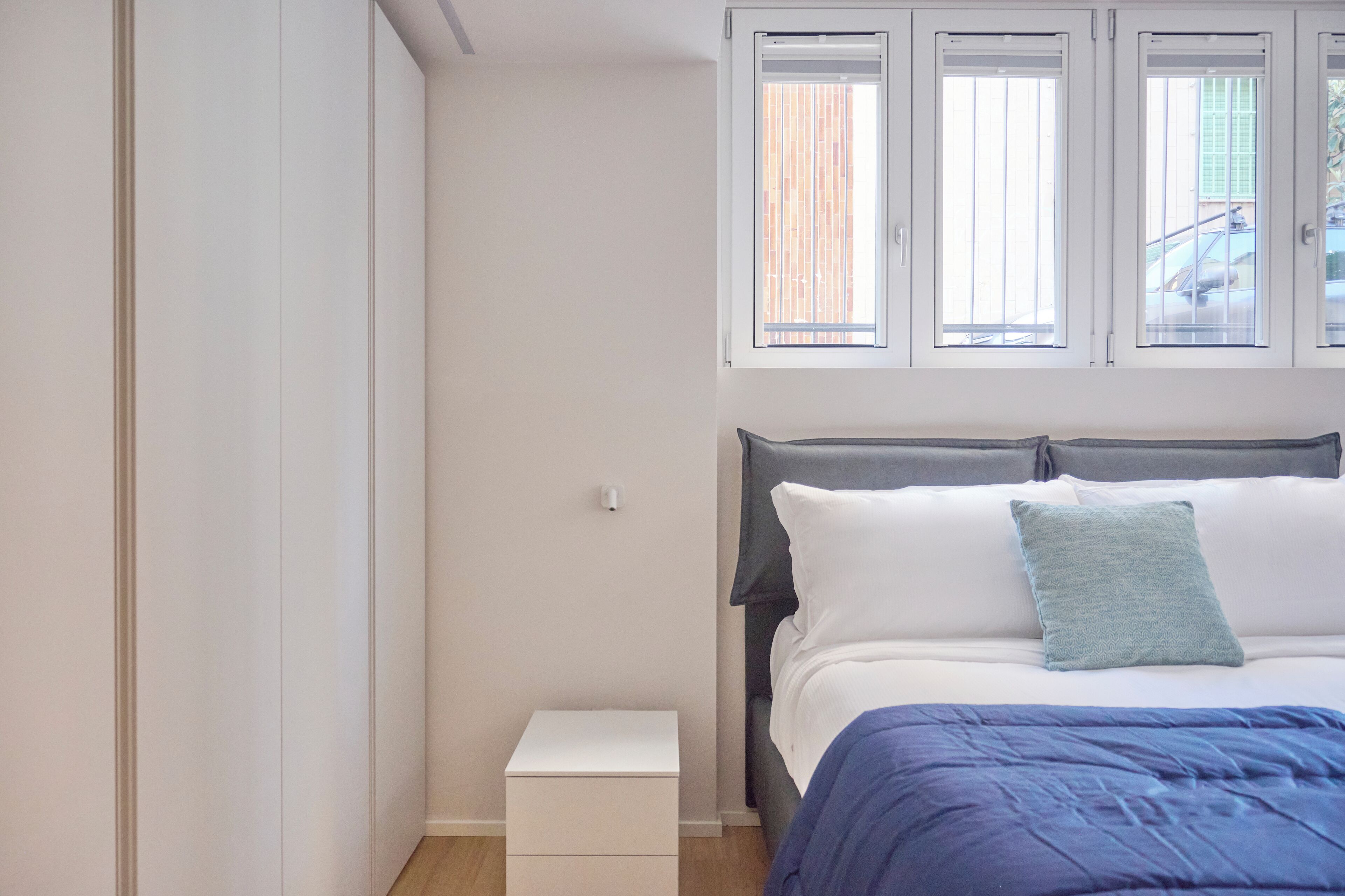A bedroom with a bed, a nightstand, and a window with blinds.