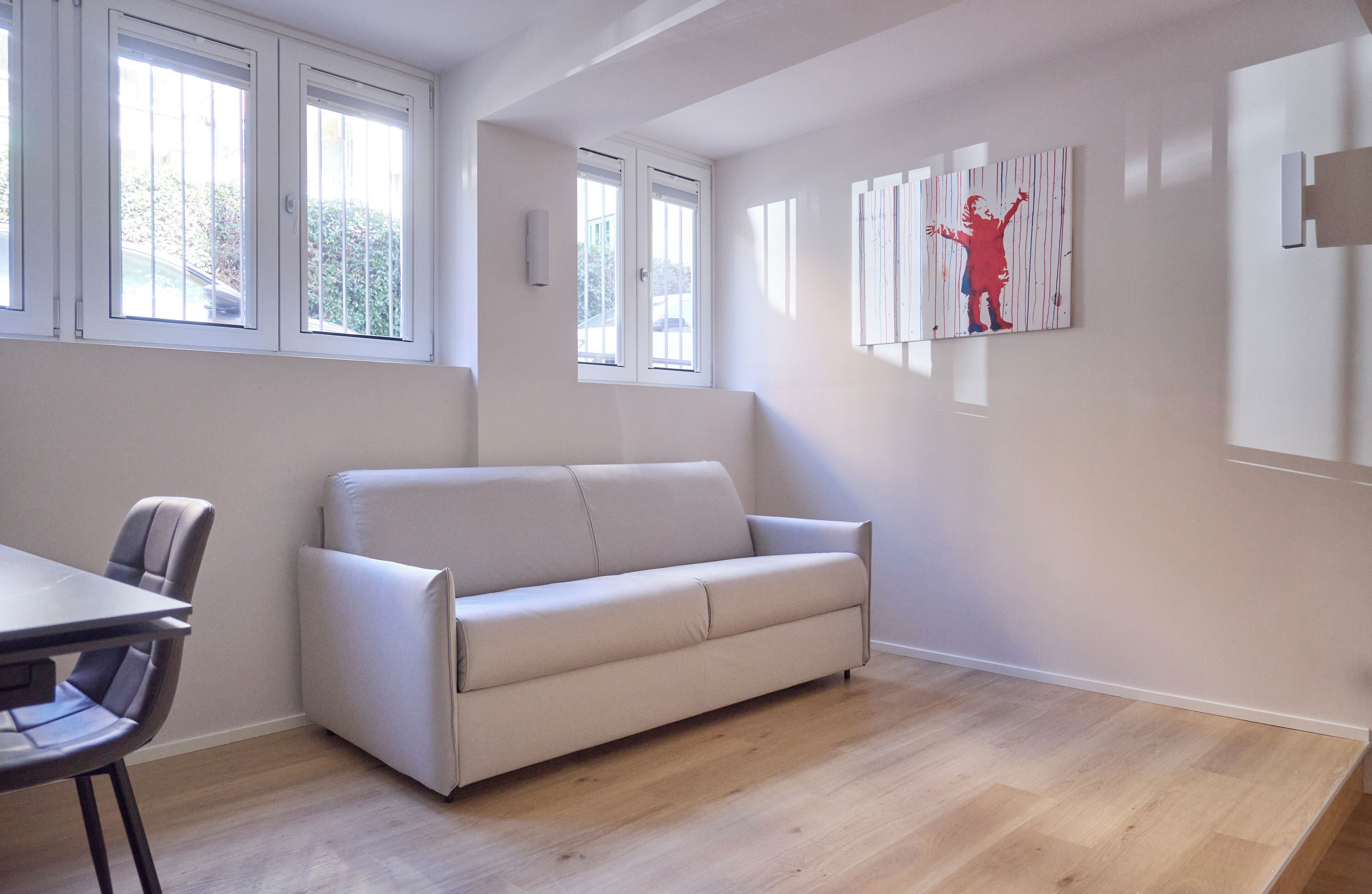 Ein modernes Wohnzimmer mit einem weißen Sofa, einem Esstisch mit Stühlen und einem Bild an der Wand.
