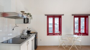A compact kitchen with a black countertop, white cabinets, and a red-framed window. - GuestReady - Oporto Old Town House 3 (Porto)