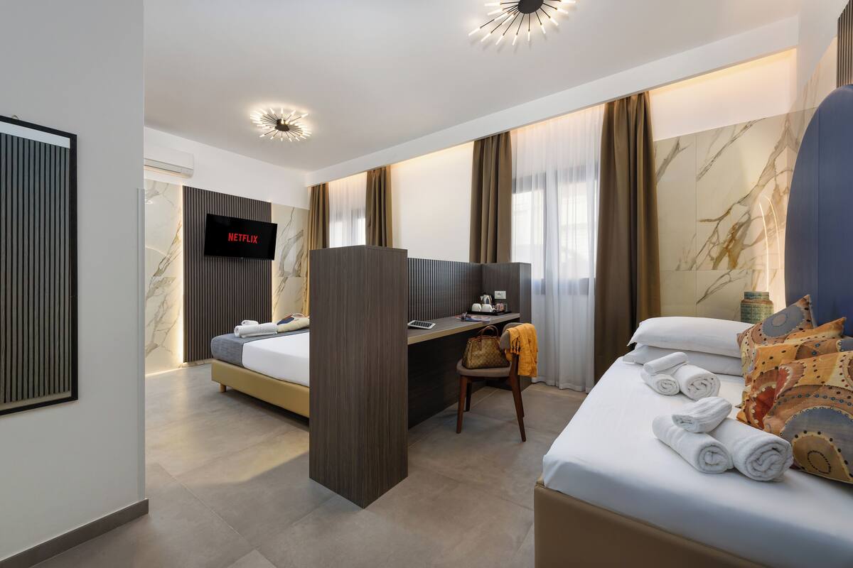 A modern hotel room with a bed, desk, and TV.