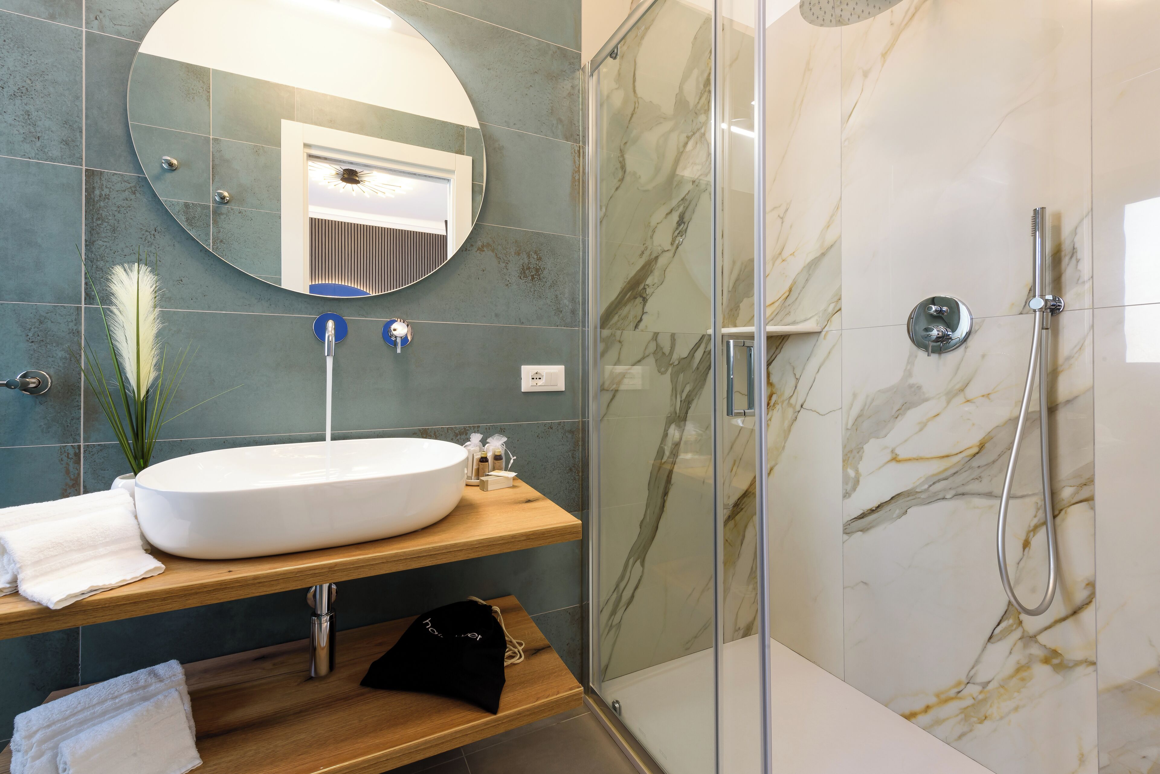 A bathroom with a large oval sink, a mirror, a shower enclosure, and a towel rack.