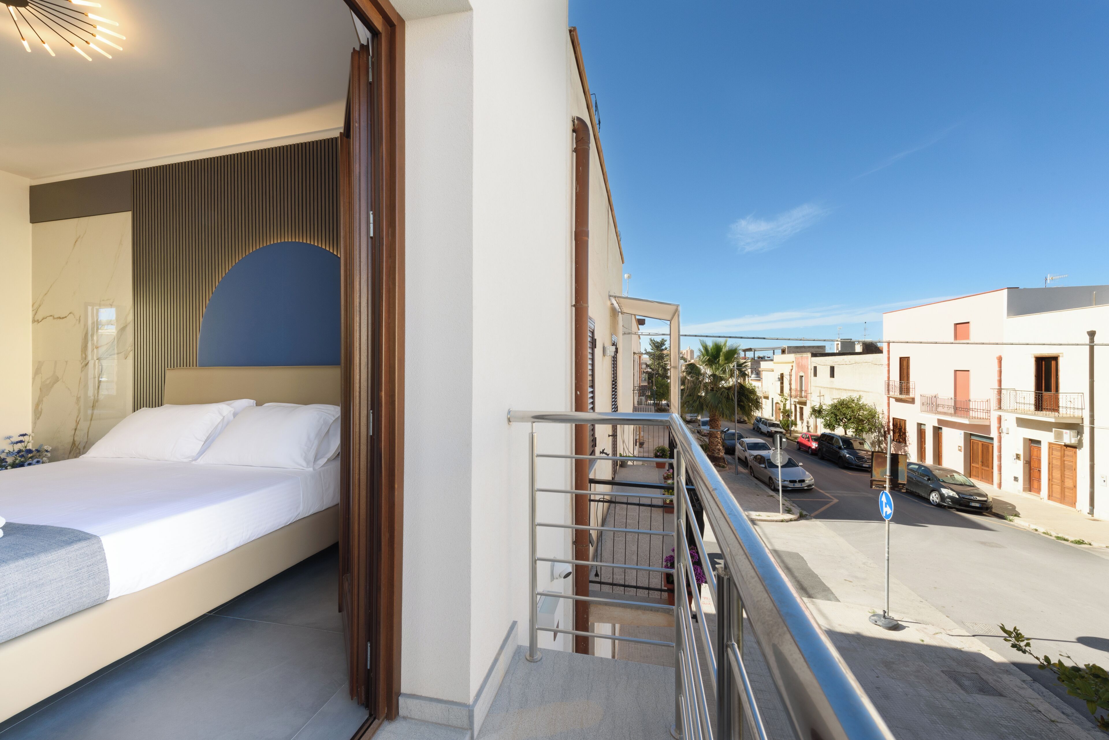 Une chambre moderne avec un lit, une vue sur la rue et une rambarde de balcon.