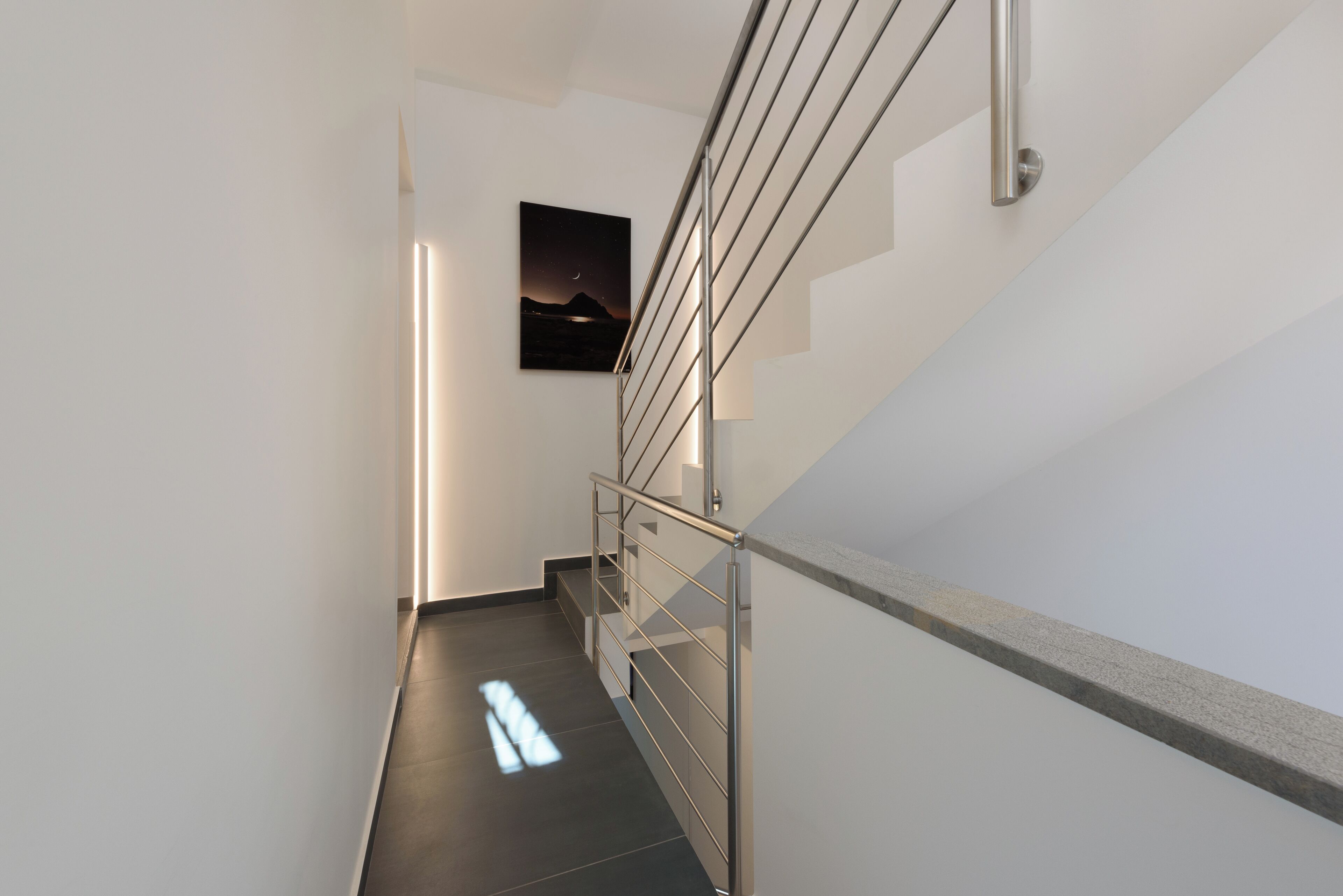 A modern staircase with metal railings and a wall-mounted picture.