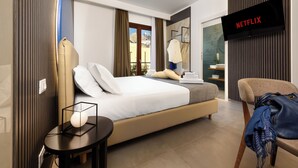 Habitación de hotel moderna con una cama grande, un televisor montado en la pared y vistas al exterior.