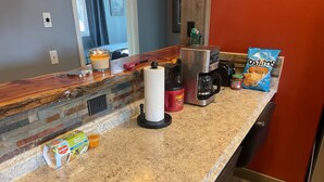 Eine Küchenarbeitsplatte mit Kaffeemaschine, Mixer, Chips, Cornflakes und einer Kerze.