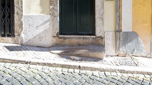 A building with a dark green door, a number '12' above it, and a small sign on the right. - Saudade Center Alfama II (Lisbon)