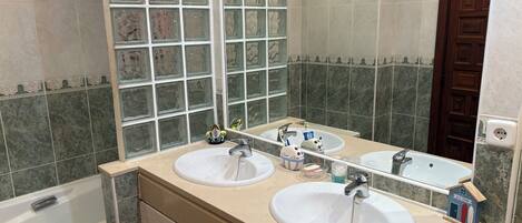 Un baño con dos lavamanos, un espejo y una ventana con bloques de vidrio decorativos.