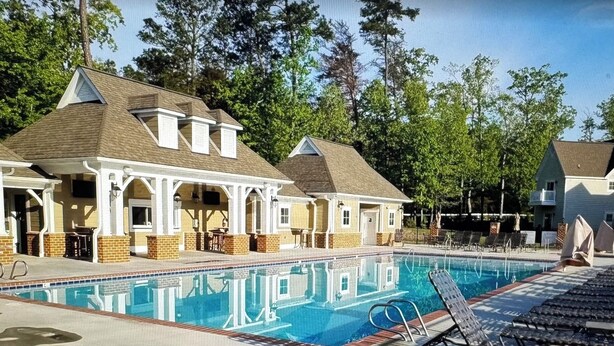 A swimming pool with lounge chairs and a covered patio area. - Charming 2-bedroom estate in beautiful Williamsburg with WiFi, fitness room (Williamsburg)