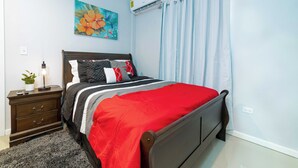 A bedroom with a bed, a nightstand, a potted plant, and a wall-mounted air conditioner. - Stylish 1-bedroom apartment in delightful Buckleys with WiFi, AC (Buckleys)