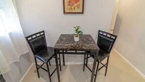 A small dining area with a marble table and two black chairs, a potted plant on the table, and a framed artwork on the wall. - Stylish 1-bedroom apartment in delightful Buckleys with WiFi, AC (Buckleys)