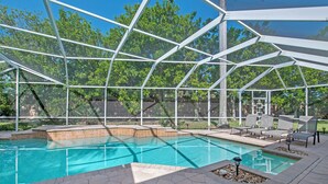 Ein Schwimmbad mit Glasveranda, umgeben von Liegestühlen und einer Terrasse.