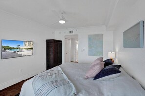 Une chambre avec un lit, une armoire, un ventilateur de plafond et un tableau au mur.