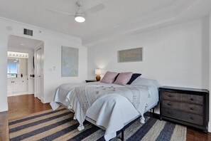 A bedroom with a bed, nightstand, dresser, and a large window. - Le Petit Italie ,Water view 2/2 with pool (Sunny Isles Beach)