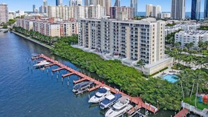 A high-rise hotel with multiple floors, a marina with boats docked, and a city skyline in the background.